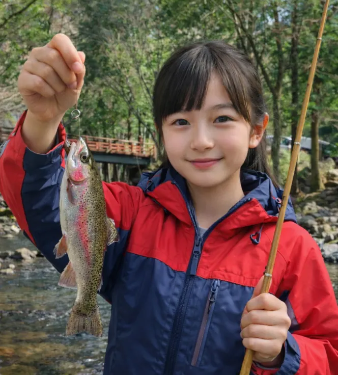 神越渓谷マス釣り場でニジマスの釣果を得た少女.webp